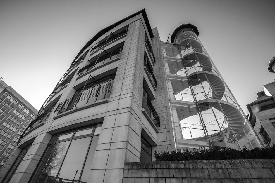 Black and white view of a modern urban building with a striking spiral staircase