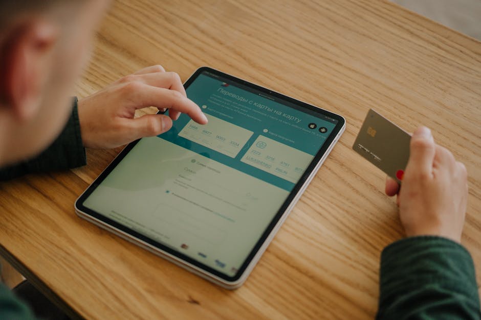 Person making an online payment using a tablet and credit card on a wooden desk