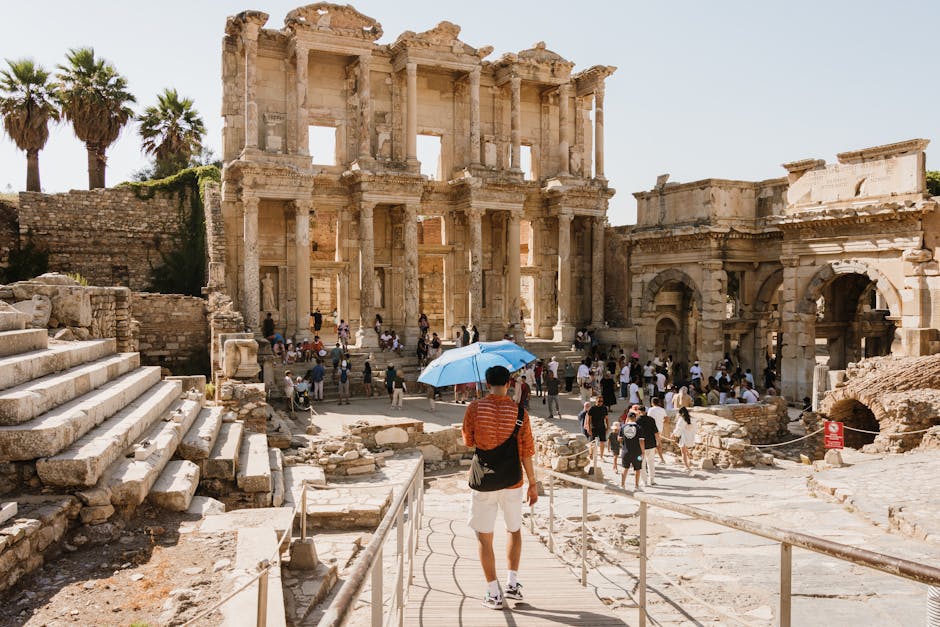 Tourists visiting the majestic Celsus Library ruins in Ephesus under a sunny sky.
