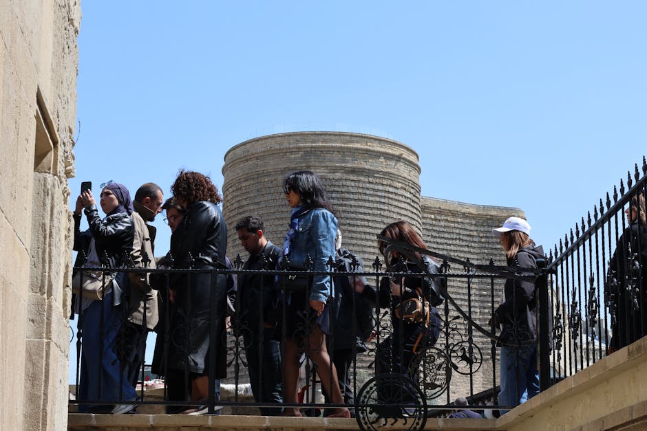 Group of tourists visiting the historic Maiden Tower in Baku under a bright sunny sky.